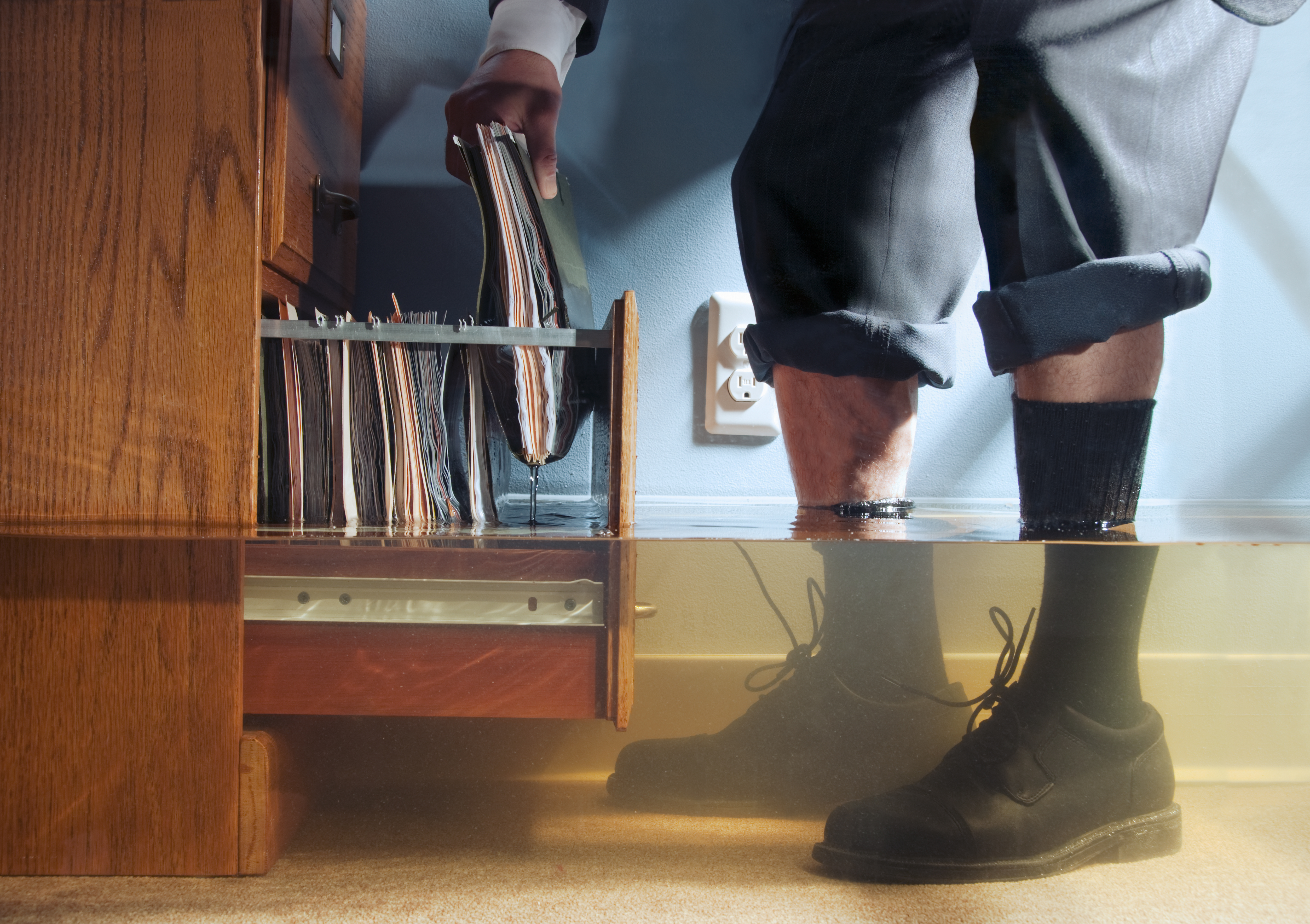 Businessman pulling files out of cabinet in flooded office, low angle