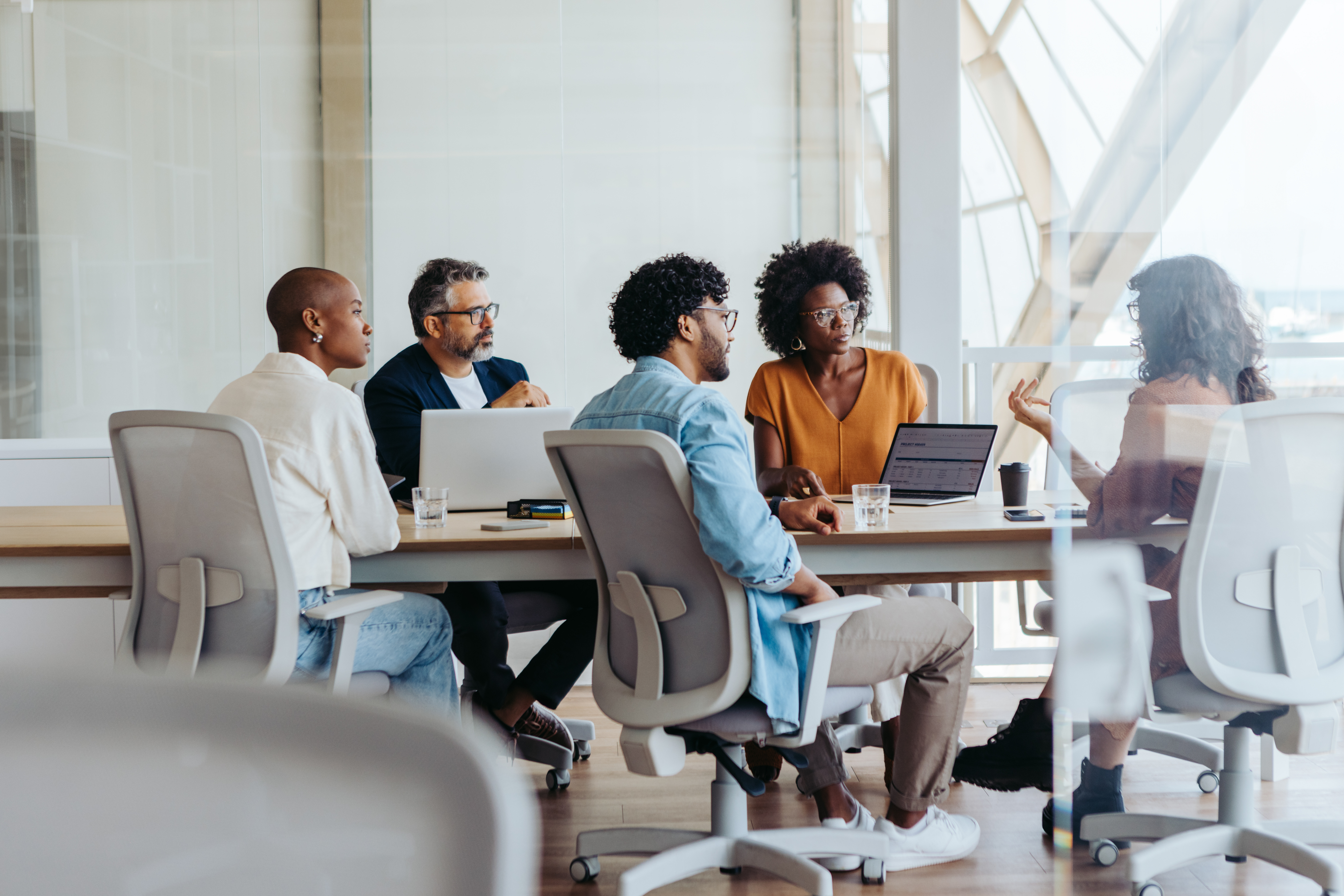 Creative group of professionals collaborates and brainstorm ideas in a modern office. Both men and women actively engage in a dynamic discussion, demonstrating teamwork and creativity.