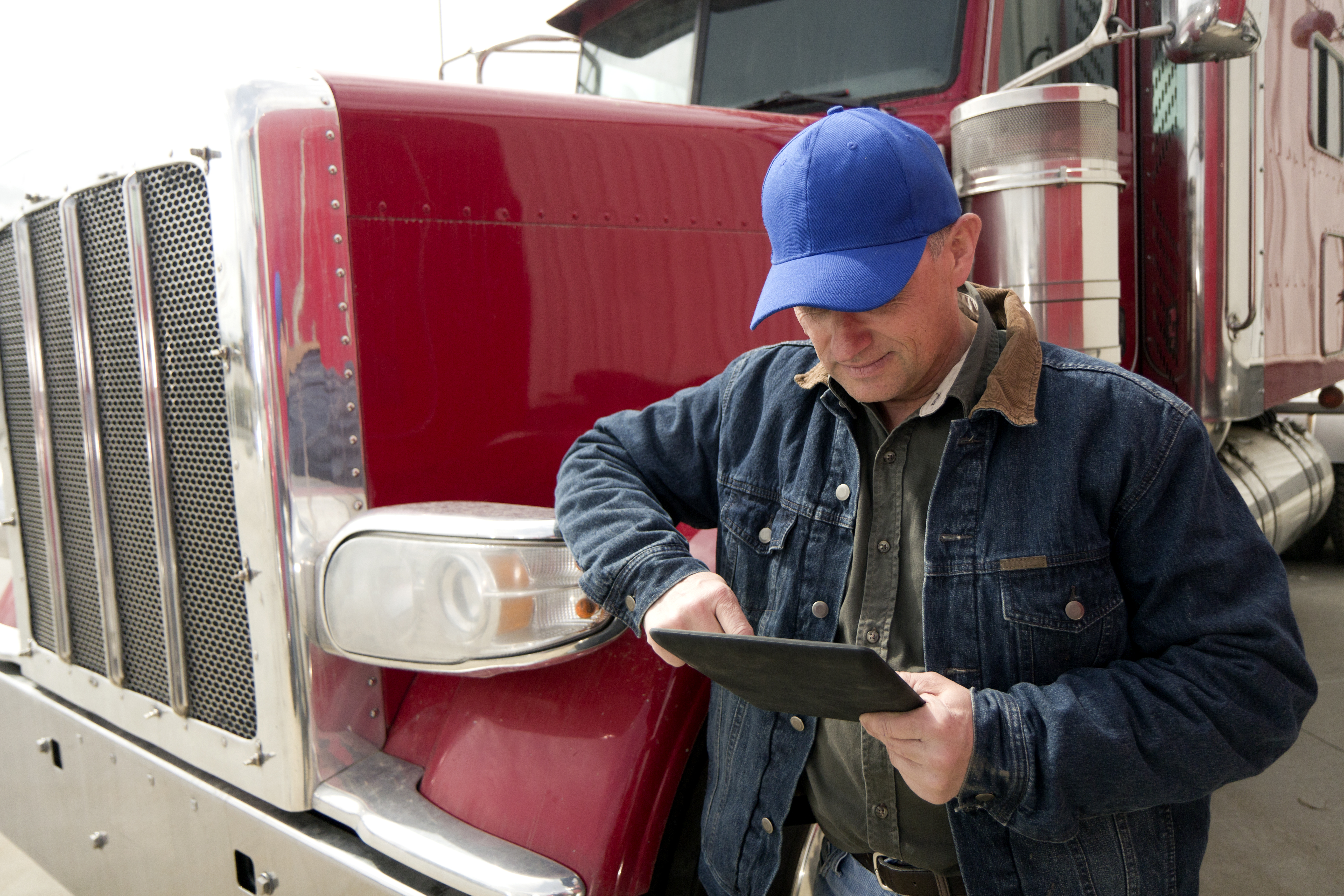 A royalty free image from the trucking industry of a truck driver and tablet PC.
