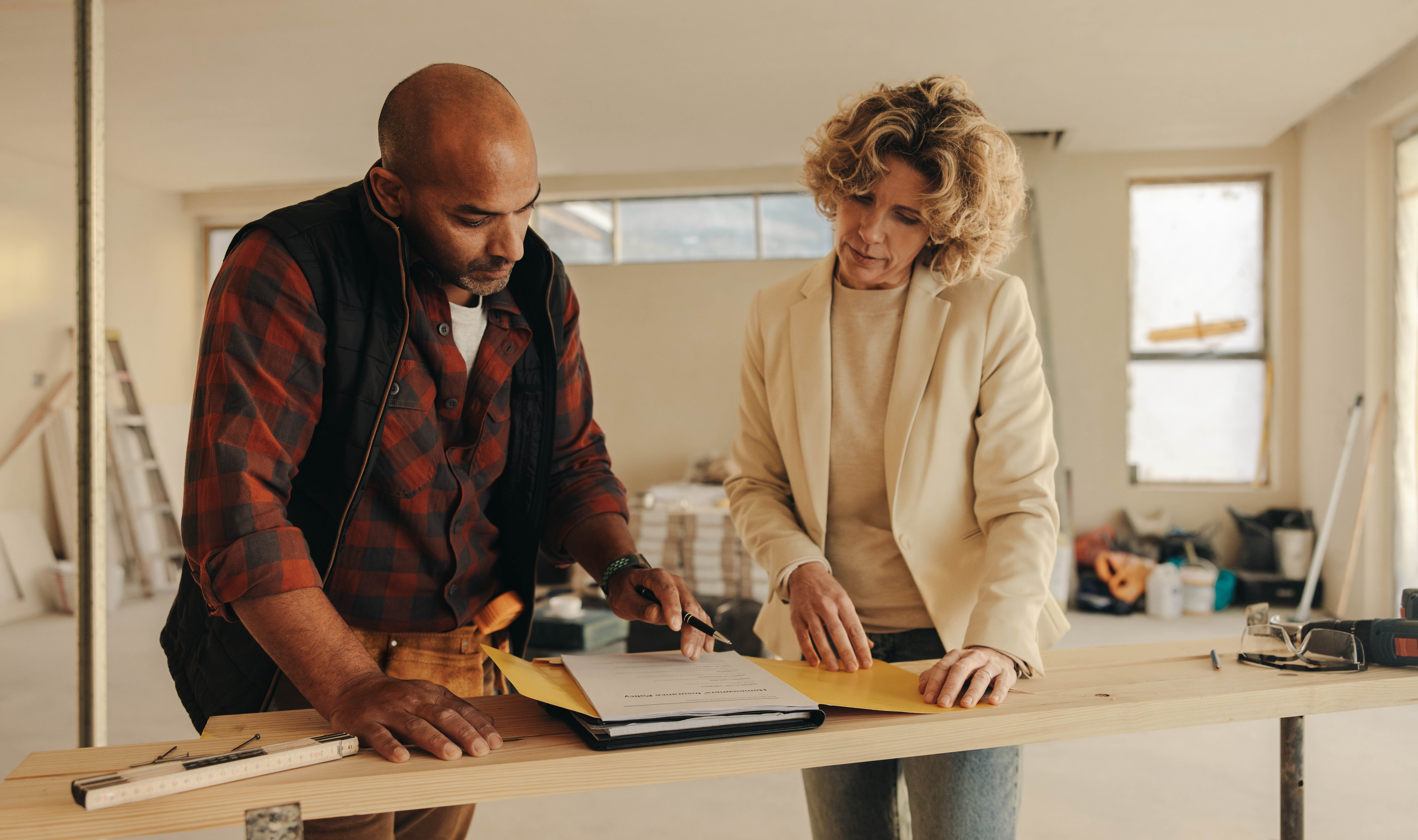 Mature contractor and female homeowner signing a contract indoors for a home renovation project. They demonstrate professionalism and dedication to their work, ensuring a successful remodeling experience.