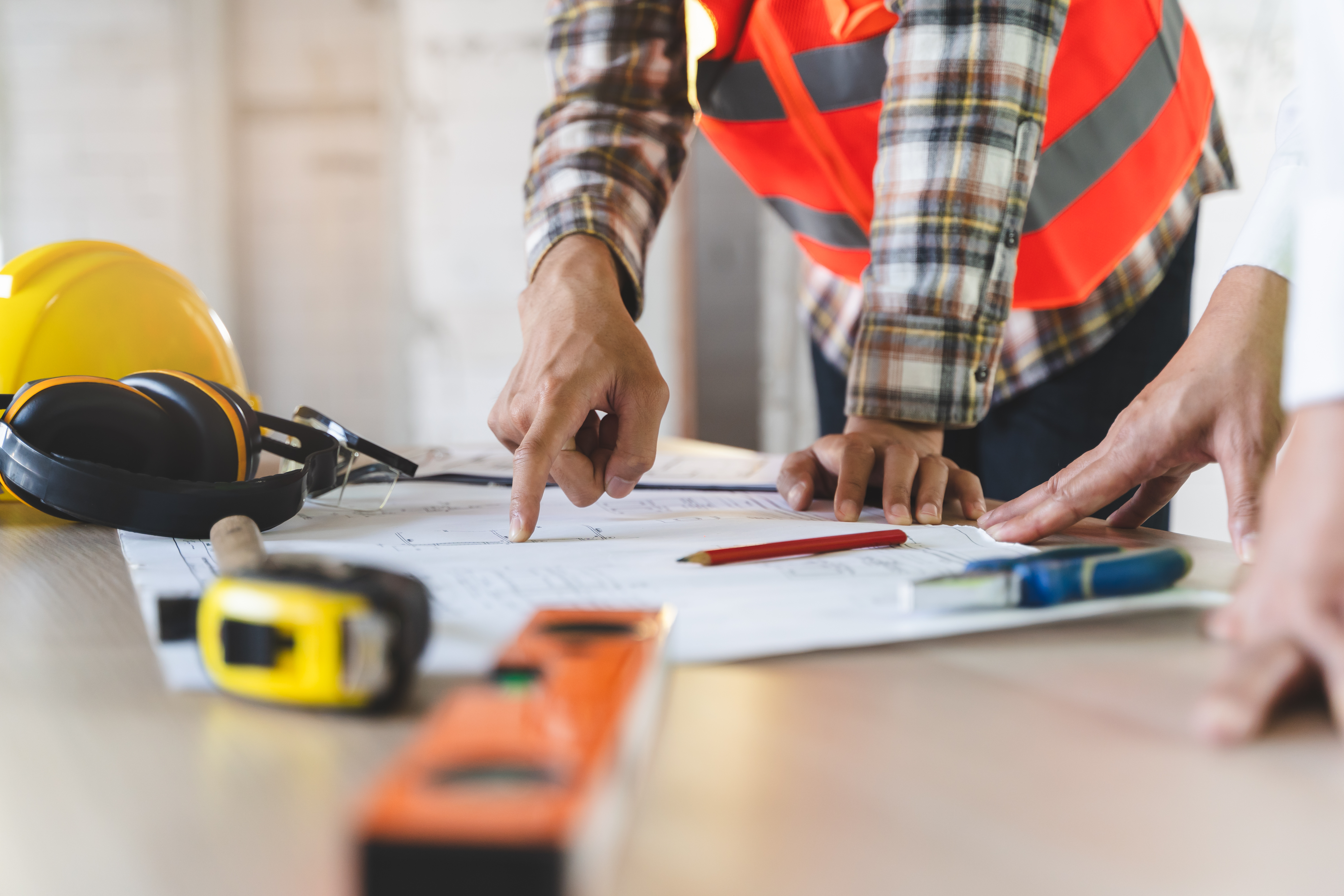 Close up hands of businessman from consultancy service discussing with project contractor and reviewing blueprint for build real estate facilities.